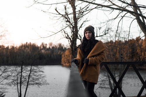 女人站在棕色木栏杆附近 · 免费素材图片