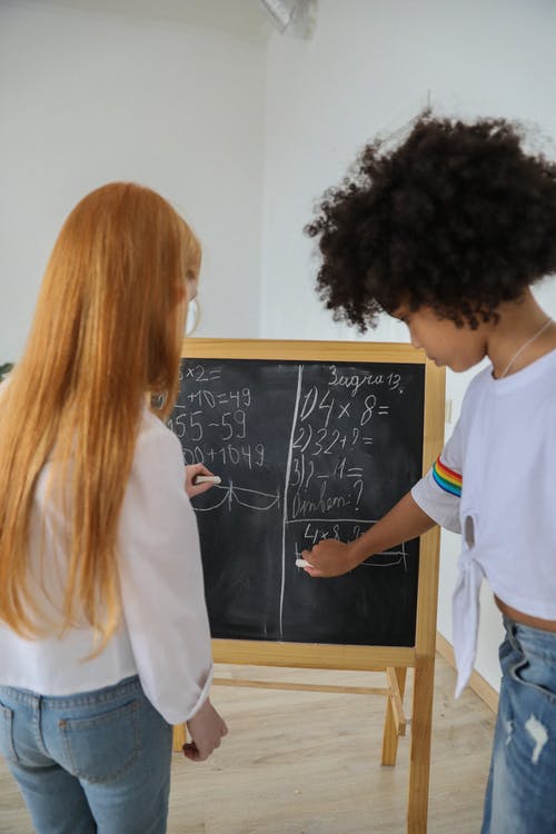 多种族的女孩在黑板上写数学方程 · 免费素材图片