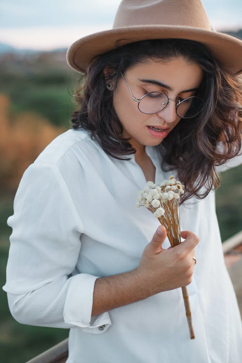 女人穿着白色的衬衫，拿着白花 · 免费素材图片