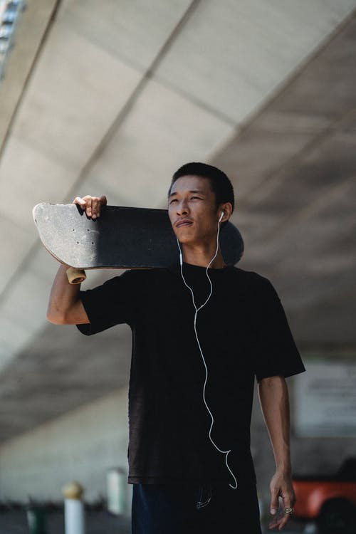 耳机在肩膀上携带滑板积极亚洲溜冰者 · 免费素材图片