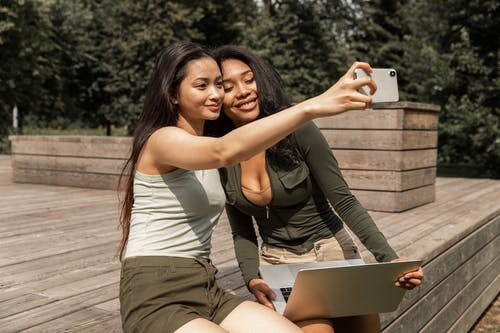 采取在智能手机的快乐的年轻不同的女朋友自拍照在公园 · 免费素材图片