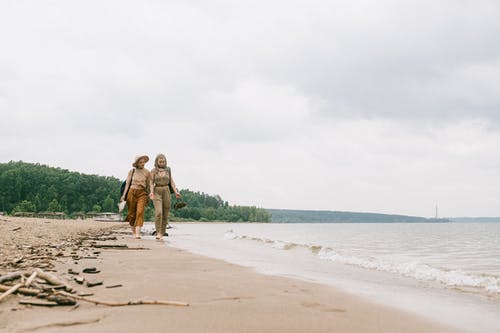 两个女人在沙滩上行走 · 免费素材图片