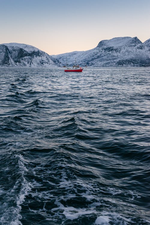 红船停在白雪皑皑的山附近的海湾 · 免费素材图片