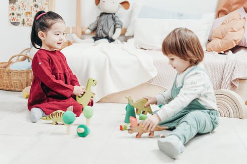 两个孩子坐下来玩玩具 · 免费素材图片