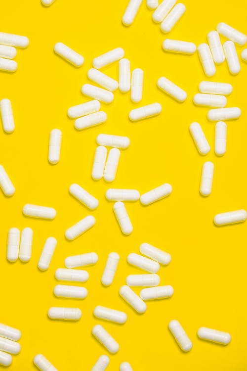 孤立在黄色背景上的白色药 · 免费素材图片