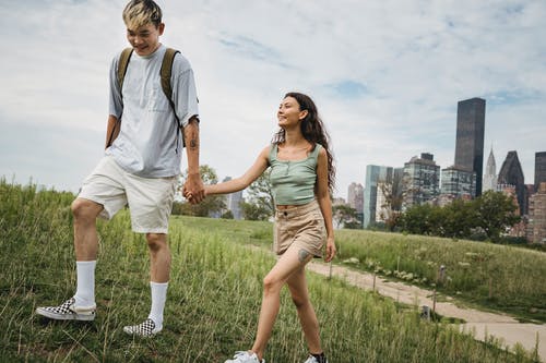 作物微笑多民族夫妇牵着的手在草山上 · 免费素材图片