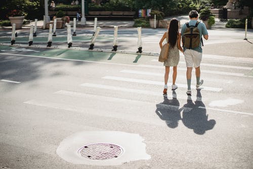 不可识别的夫妇过马路在阳光明媚的城市 · 免费素材图片
