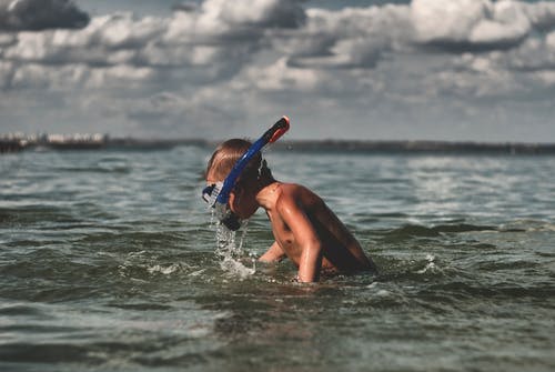 男孩在海里游泳时使用浮潜 · 免费素材图片