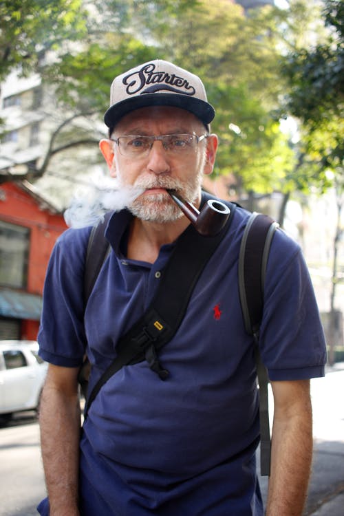 蓝色polo衫在户外吸烟的人 · 免费素材图片