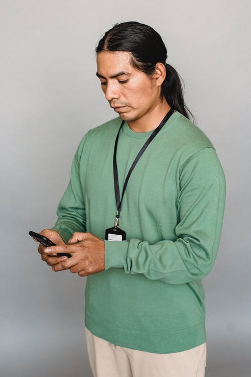 印度男子在工作室里浏览智能手机 · 免费素材图片