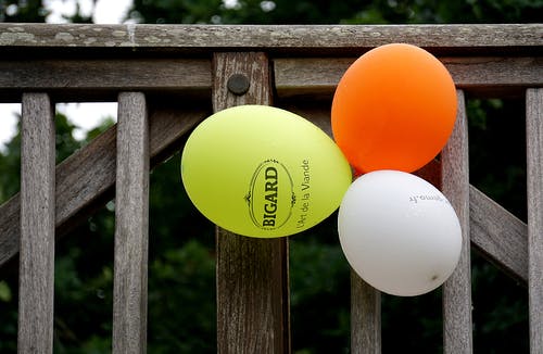 灰色的木栅栏旁边的黄色橙色和白色气球 · 免费素材图片