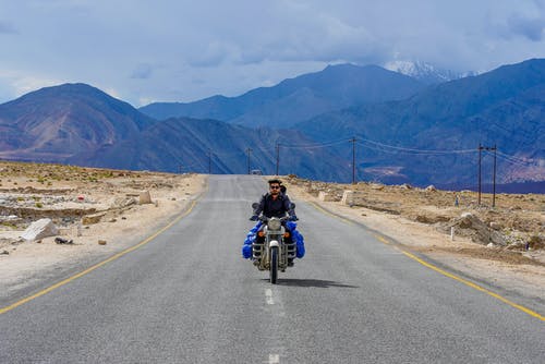 男子骑着摩托车通过混凝土路 · 免费素材图片