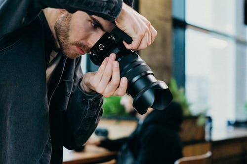 男子手持黑色单反相机 · 免费素材图片