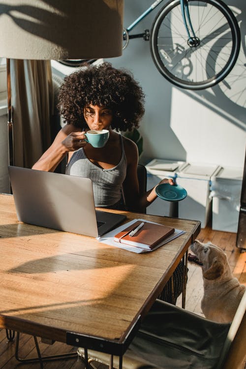 黑人女士在上网本上远程工作，喝咖啡 · 免费素材图片