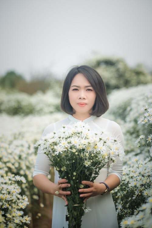 女人穿着白色的衣服，拿着白花 · 免费素材图片