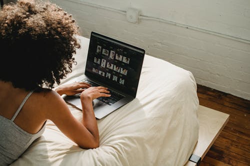 在卧室里的笔记本电脑上工作的黑女人 · 免费素材图片