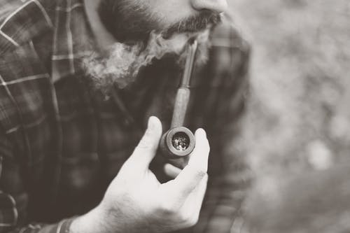 该名男子手持烟斗的灰度照片 · 免费素材图片