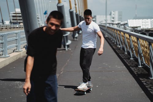 在桥上滑板的年轻快乐亚洲朋友 · 免费素材图片