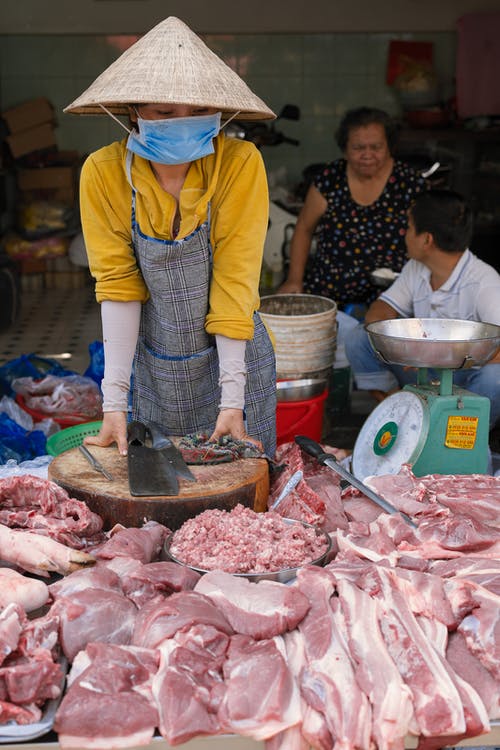 戴锥形帽子卖生肉的女人 · 免费素材图片