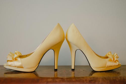 木质表面上的一双女式米色露趾高跟凉鞋 · 免费素材图片