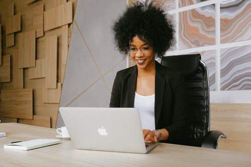 使用macbook时坐在桌旁的黑色西装外套的女人 · 免费素材图片