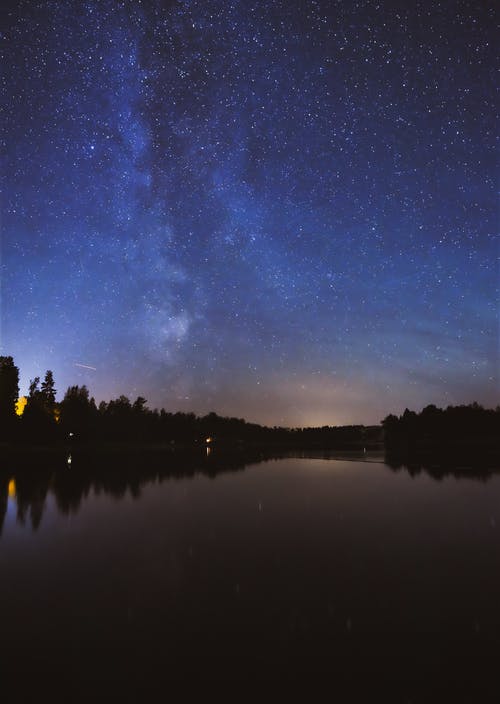 繁星点点的夜空下树对水体反射的风景摄影 · 免费素材图片