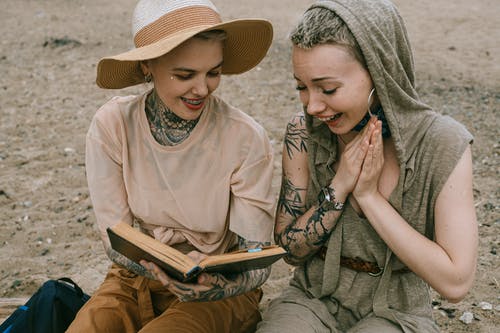 妇女在读书时笑的照片 · 免费素材图片