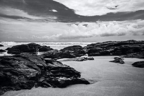 白天海边岩石的灰度摄影 · 免费素材图片