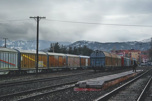 火车在白天在灰色的天空下在火车轨道上运行 · 免费素材图片