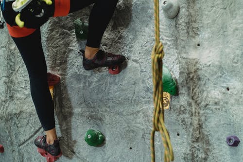 女子攀岩训练在石质灰色的墙上举行 · 免费素材图片