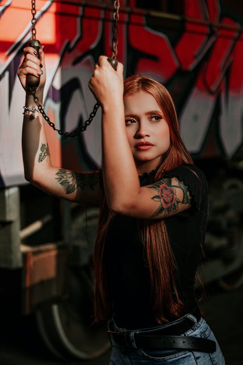 黑色衬衫的女人，在她的左手上有红色和黑色的花纹身 · 免费素材图片