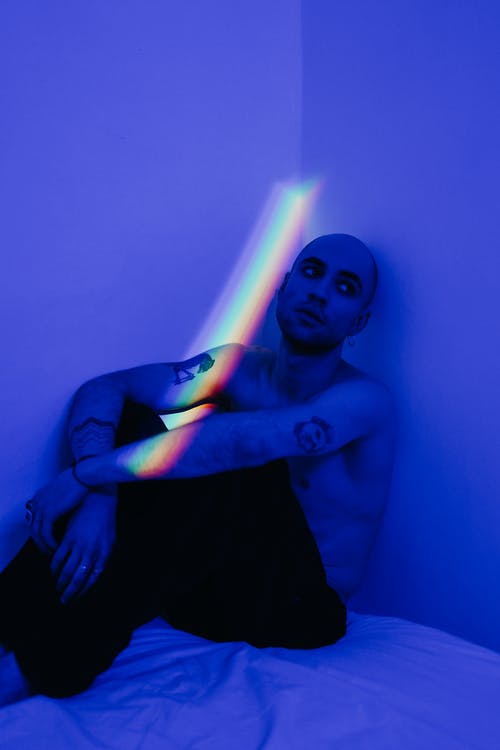 男子倚在蓝光房间的墙上 · 免费素材图片
