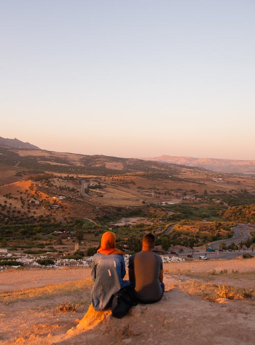 不可识别的夫妇在丘陵山谷的农村定居点享受日落 · 免费素材图片
