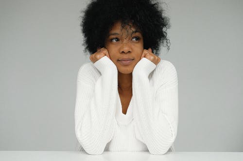 一个女人抱着她的下巴的白毛衣的肖像 · 免费素材图片