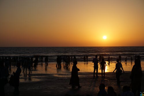 人们在日落时在海滩上的剪影 · 免费素材图片