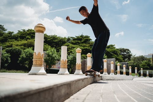 在城市的人行道上滑板的亚洲运动员 · 免费素材图片
