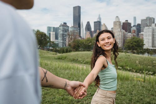 高兴的民族女友在散步时与男友手牵着手 · 免费素材图片