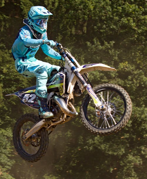 蓝色的mtx西装骑在空气中的蓝色和黄色的污垢摩托车的人 · 免费素材图片
