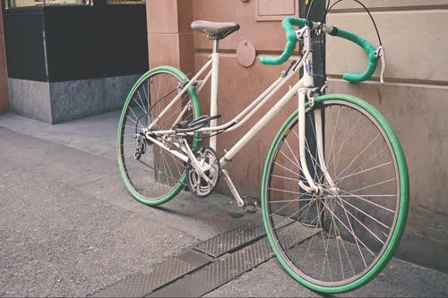 白色和绿色的自行车，靠在墙上 · 免费素材图片
