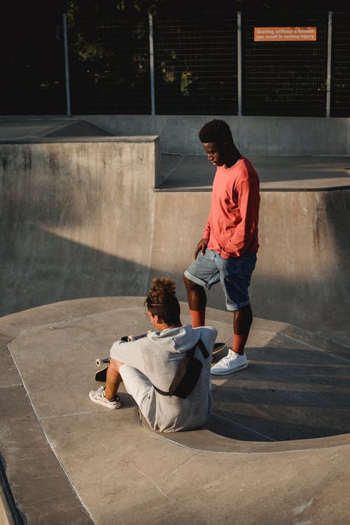 匿名的多种族运动员与滑板在城市坡道上相互作用 · 免费素材图片