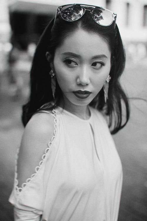 时髦的亚裔女子，站在模糊的街道上 · 免费素材图片