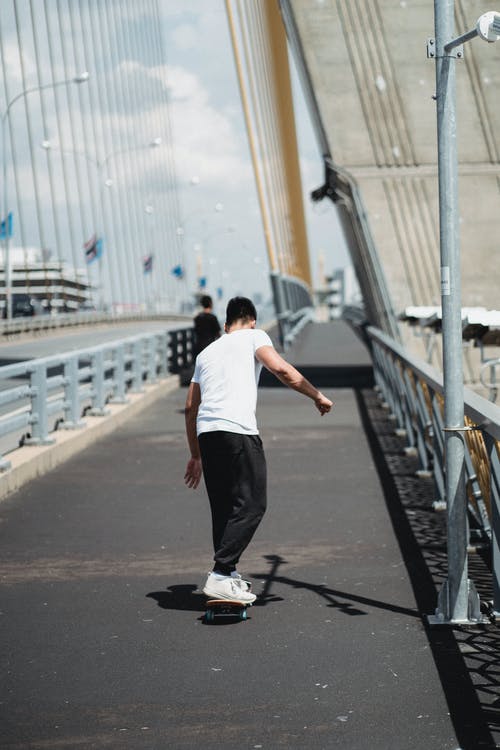 无法识别的运动员在城里的桥上滑板 · 免费素材图片