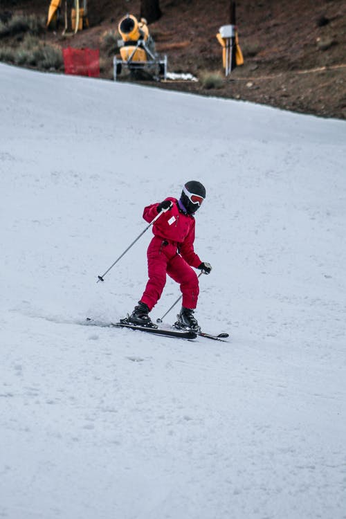 红夹克和红裤子骑在雪地滑雪上的人 · 免费素材图片