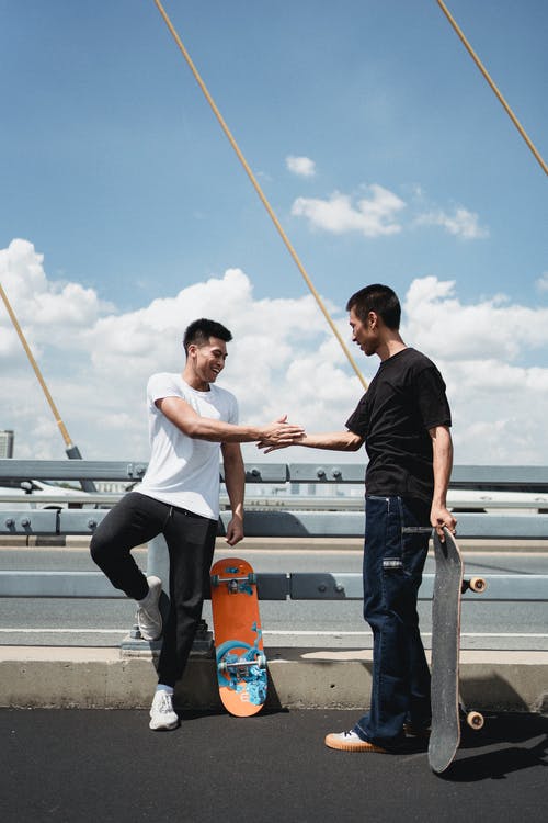 亚洲滑板手在吊桥上互相问候 · 免费素材图片