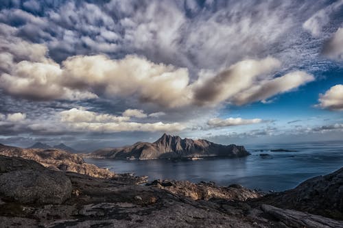 在蓝色的大海，在灰色的云层和蓝天下的洛矶山脉 · 免费素材图片