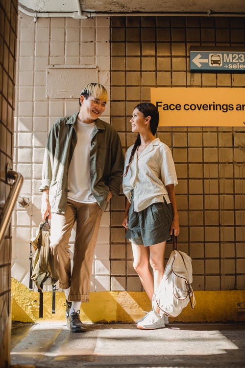 性格开朗的亚洲夫妇站在瓷砖的墙旁和谈话 · 免费素材图片