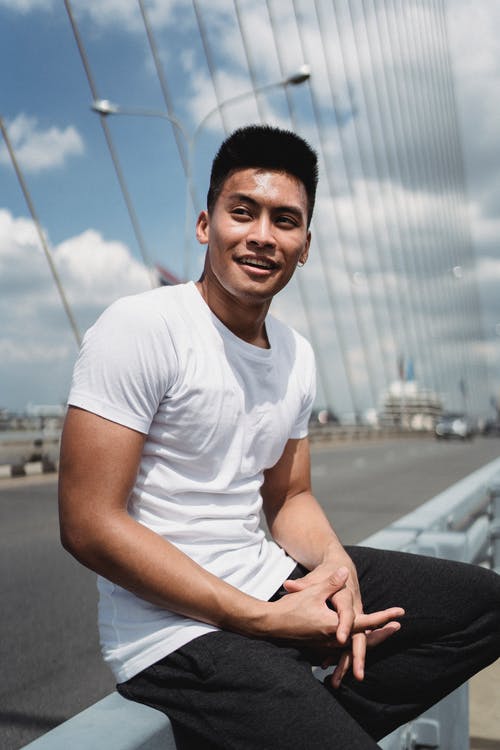 性格开朗的亚洲人，坐在栅栏上 · 免费素材图片