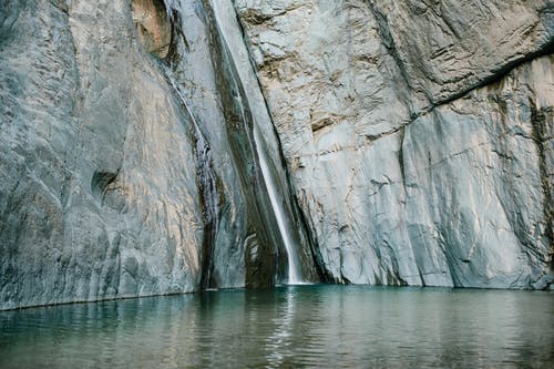 在波纹池塘附近的山中快速瀑布 · 免费素材图片