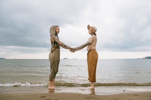 手牵着手在海滩上的妇女 · 免费素材图片
