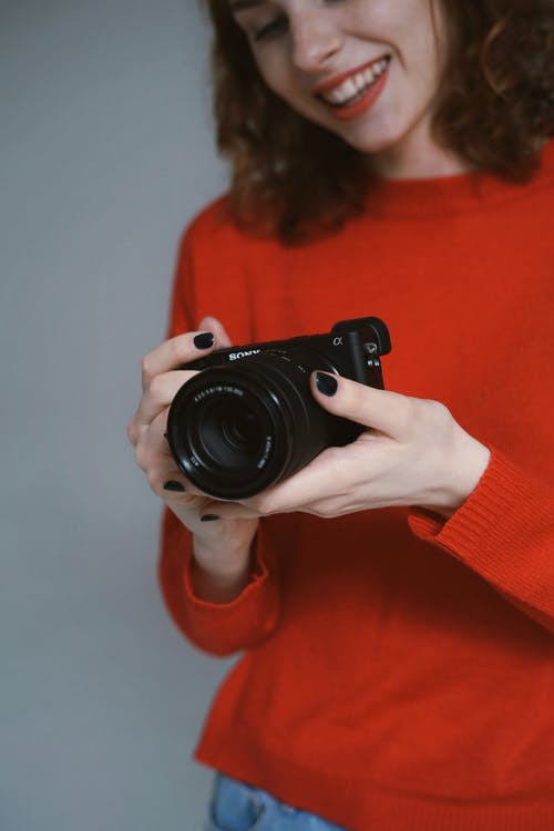 女人拿着一个黑色的数码单反相机 · 免费素材图片
